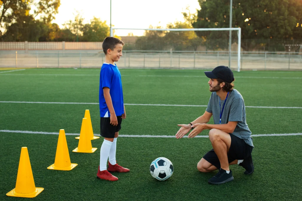 Football Trainer Teaching Kid Side View